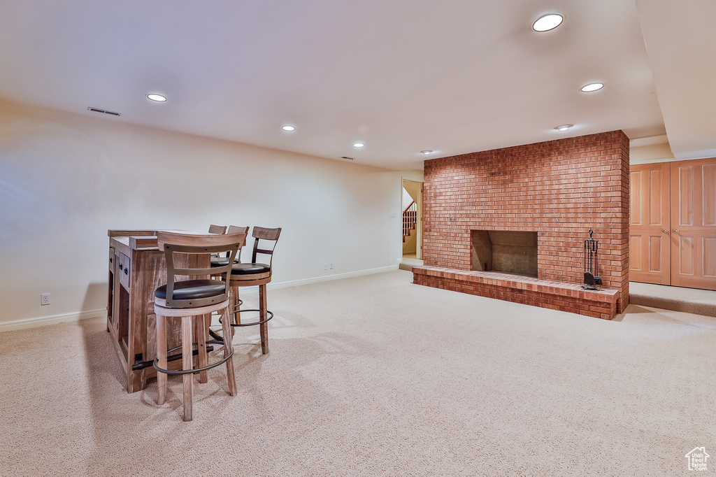 Dining room featuring a brick fireplace, light carpet, and brick wall