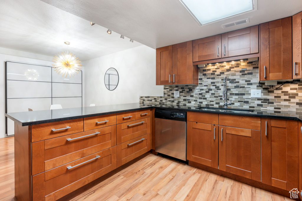 Kitchen with sink, stainless steel dishwasher, kitchen peninsula, and light hardwood / wood-style flooring