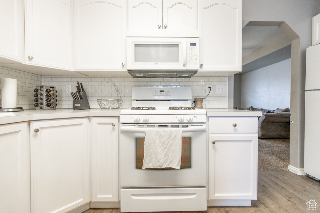 Kitchen featuring white cabinets, backsplash, white appliances, and light hardwood / wood-style flooring