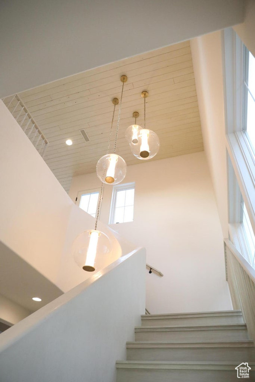 Staircase featuring a notable chandelier, a wealth of natural light, and a high ceiling