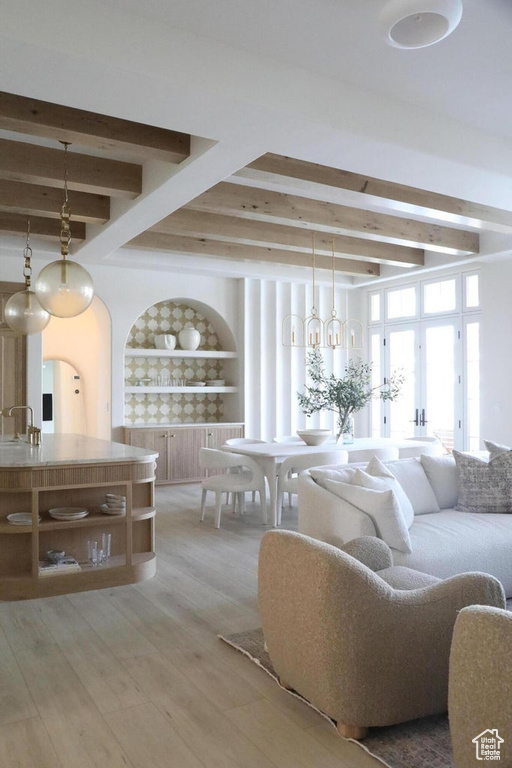 Living room featuring light wood-type flooring, built in shelves, a chandelier, french doors, and beamed ceiling