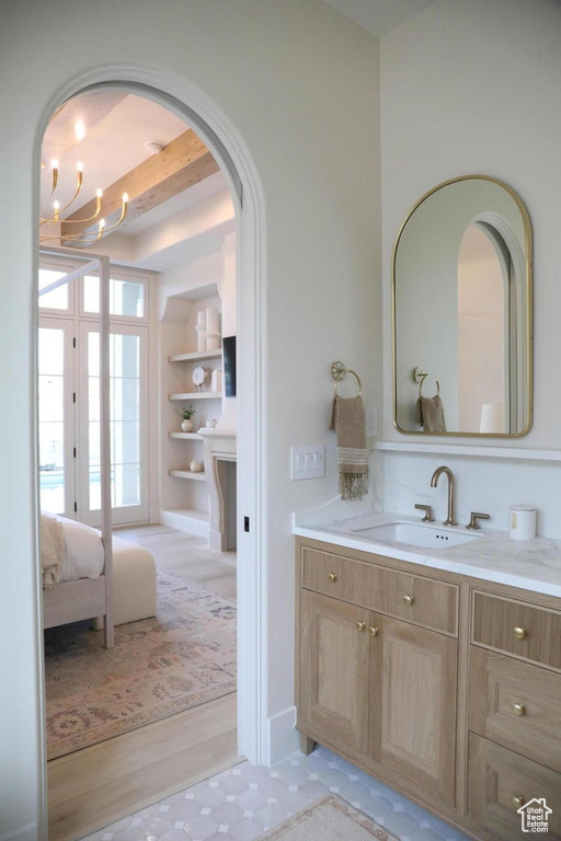 Bathroom featuring an inviting chandelier, vanity, beam ceiling, and wood-type flooring