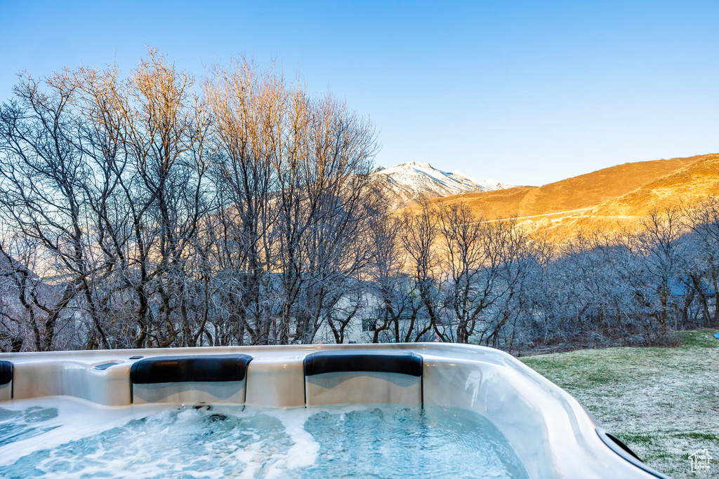Snow covered pool featuring a mountain view and a hot tub