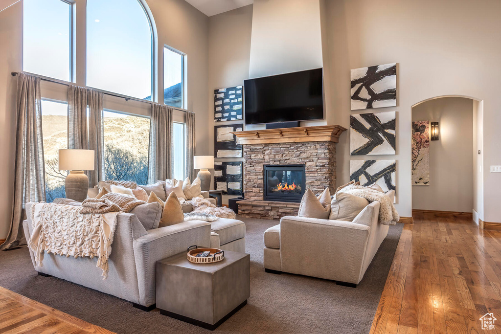 Living room featuring a stone fireplace, dark hardwood / wood-style flooring, and a towering ceiling