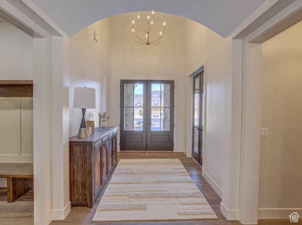 Foyer entrance featuring wood-type flooring, a notable chandelier, and french doors
