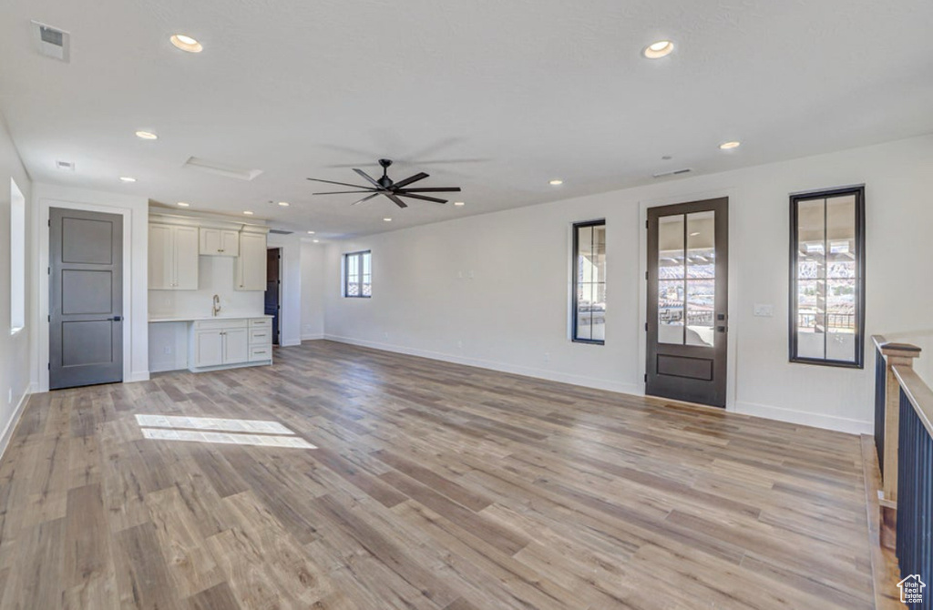 Unfurnished living room with light hardwood / wood-style floors, a wealth of natural light, and ceiling fan