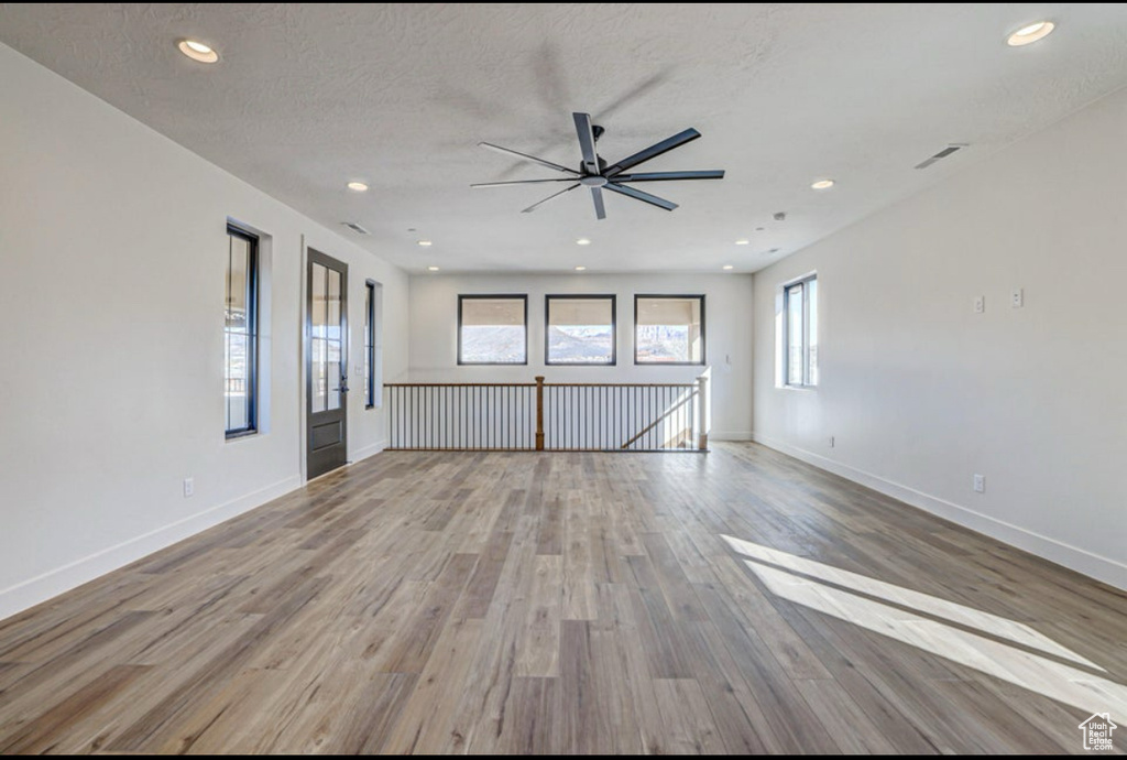 Unfurnished room featuring a textured ceiling, ceiling fan, and light hardwood / wood-style flooring