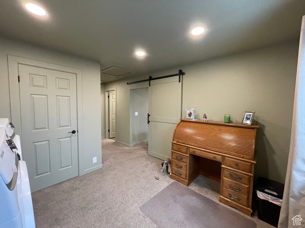 Carpeted home office featuring a barn door