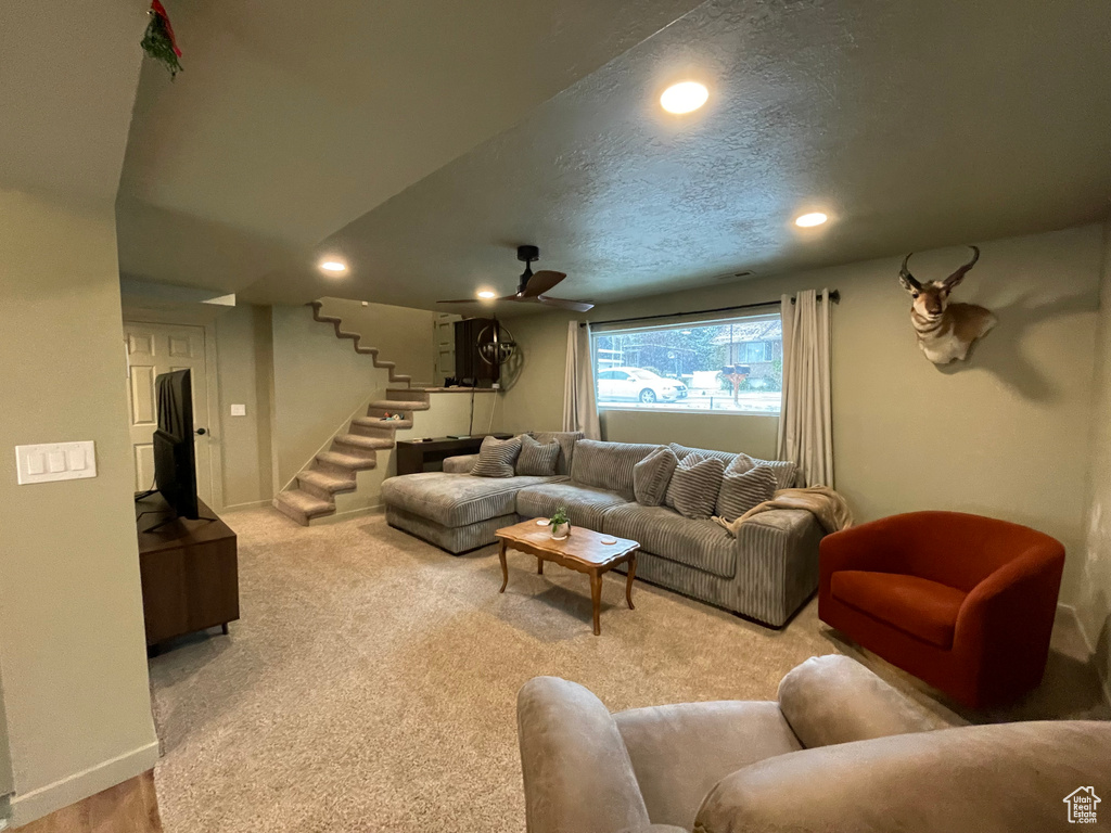 Carpeted living room with ceiling fan and a textured ceiling
