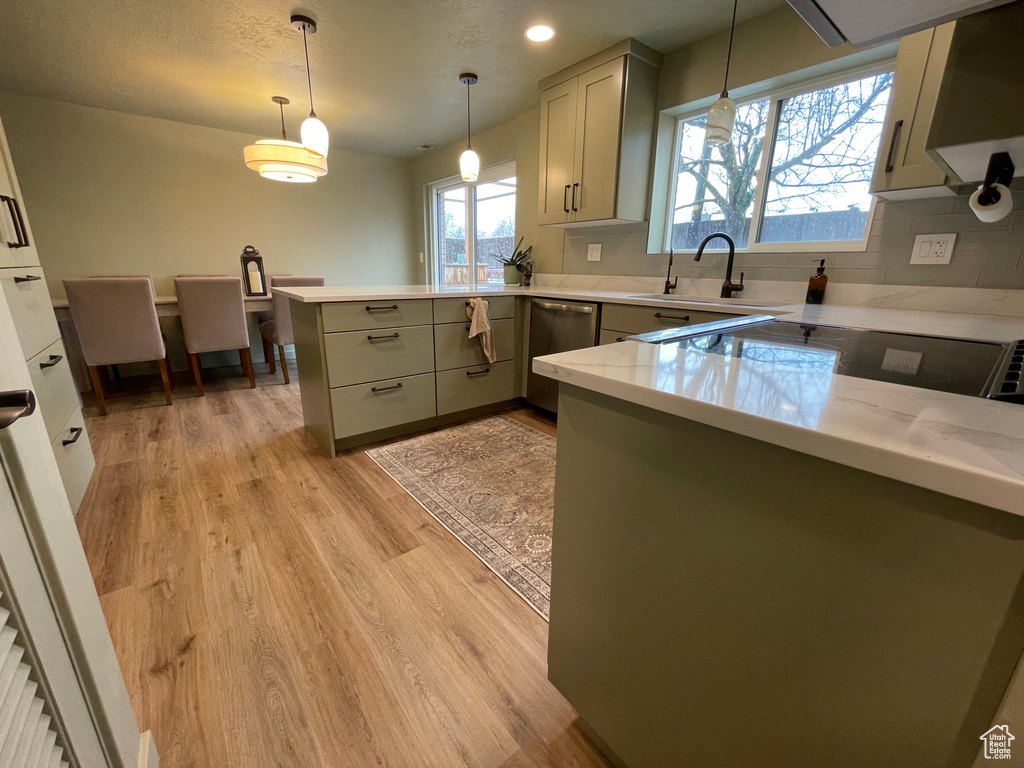 Kitchen featuring pendant lighting, sink, kitchen peninsula, light hardwood / wood-style floors, and dishwasher