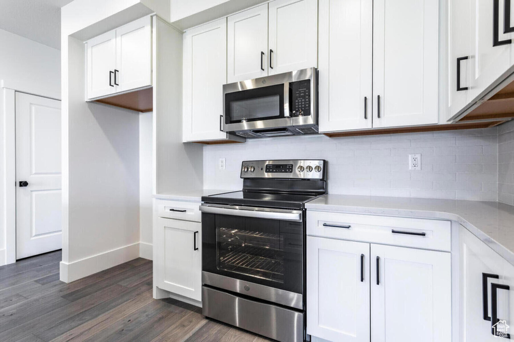 Kitchen featuring white cabinetry, stainless steel appliances, tasteful backsplash, and dark hardwood / wood-style floors