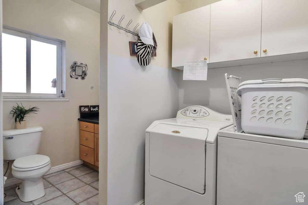 Clothes washing area featuring washing machine and dryer and light tile flooring