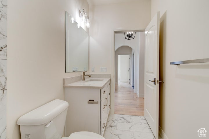 Bathroom with a chandelier, tile flooring, toilet, and oversized vanity