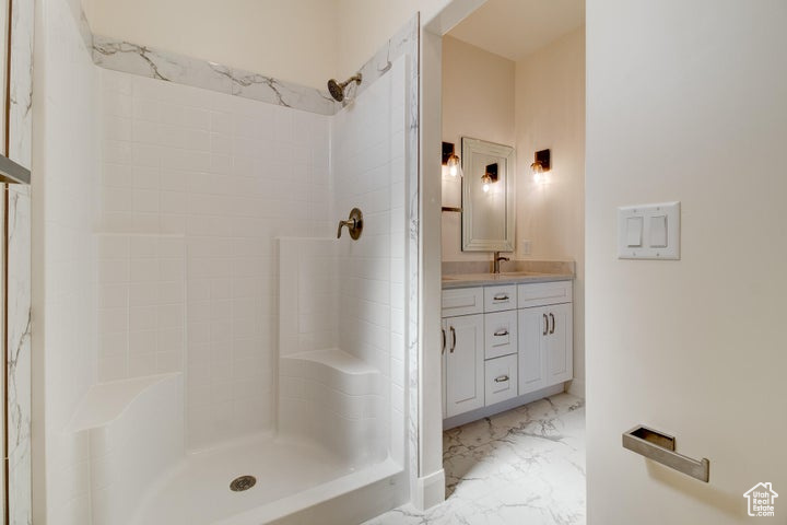 Bathroom featuring tile floors, a tile shower, and double sink vanity