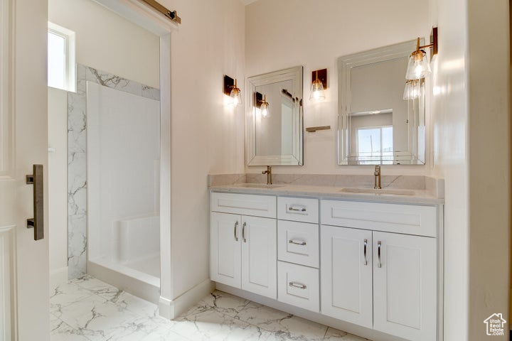 Bathroom with double sink vanity, tile flooring, and walk in shower