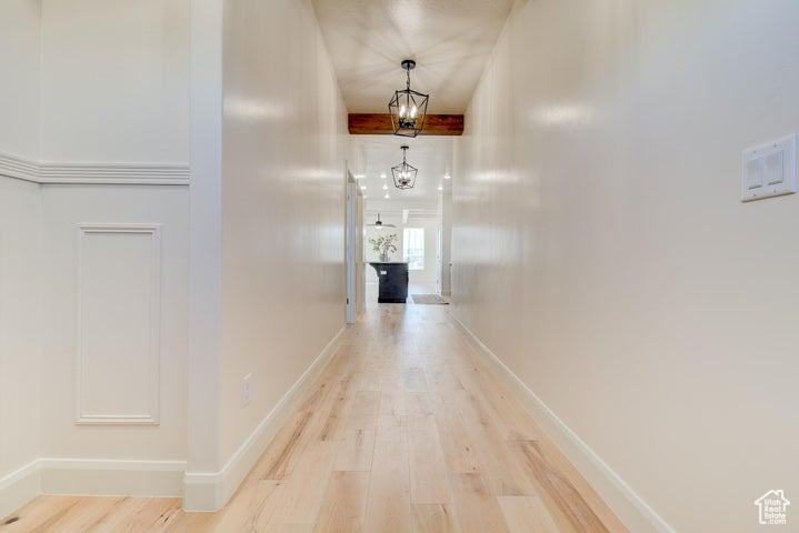 Corridor with an inviting chandelier and light hardwood / wood-style floors
