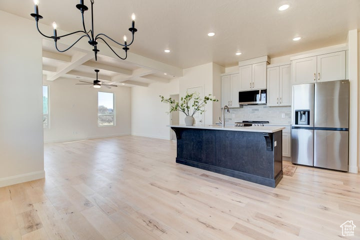 Kitchen featuring white cabinets, stainless steel appliances, light hardwood / wood-style flooring, and coffered ceiling