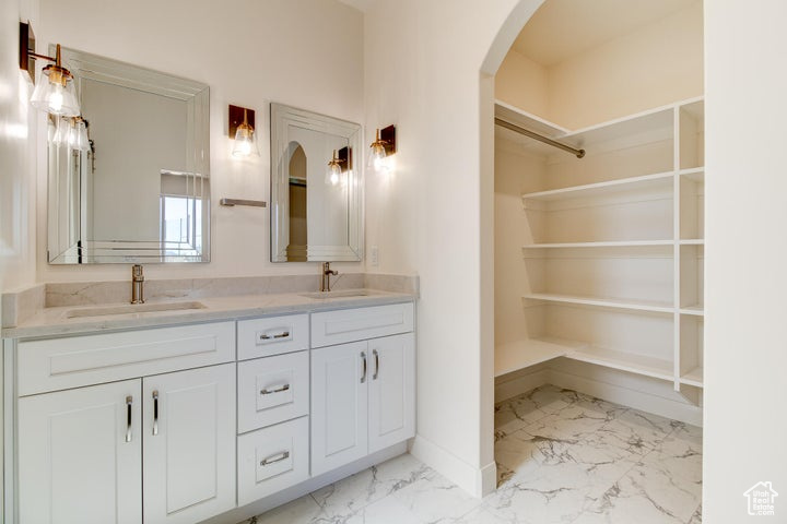 Bathroom with dual sinks, large vanity, and tile floors