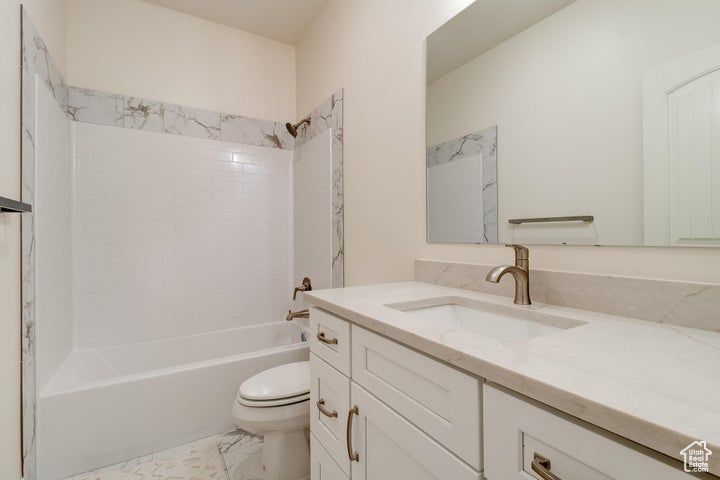 Full bathroom with tile flooring, vanity, toilet, and tiled shower / bath