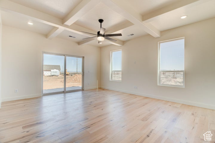 Empty room featuring ceiling fan, coffered ceiling, beamed ceiling, and light hardwood / wood-style floors