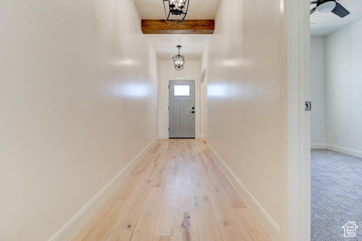 Entryway with a notable chandelier, beam ceiling, and light carpet