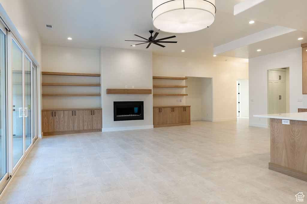 Unfurnished living room featuring a wealth of natural light, ceiling fan, and light tile floors