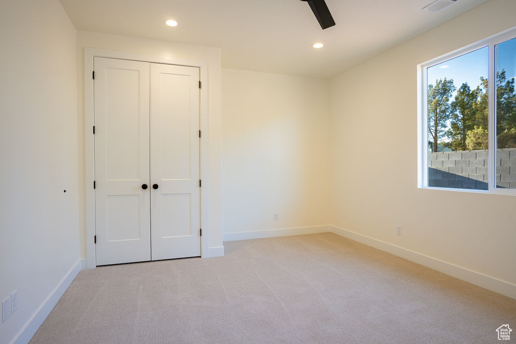 Unfurnished bedroom featuring a closet, ceiling fan, and light carpet