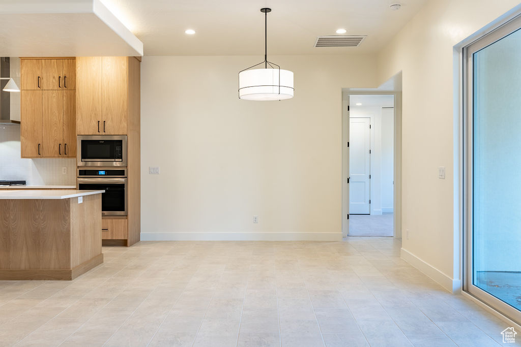 Kitchen featuring backsplash, light tile floors, stainless steel appliances, and pendant lighting