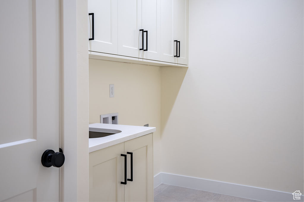 Laundry room featuring cabinets and light tile floors