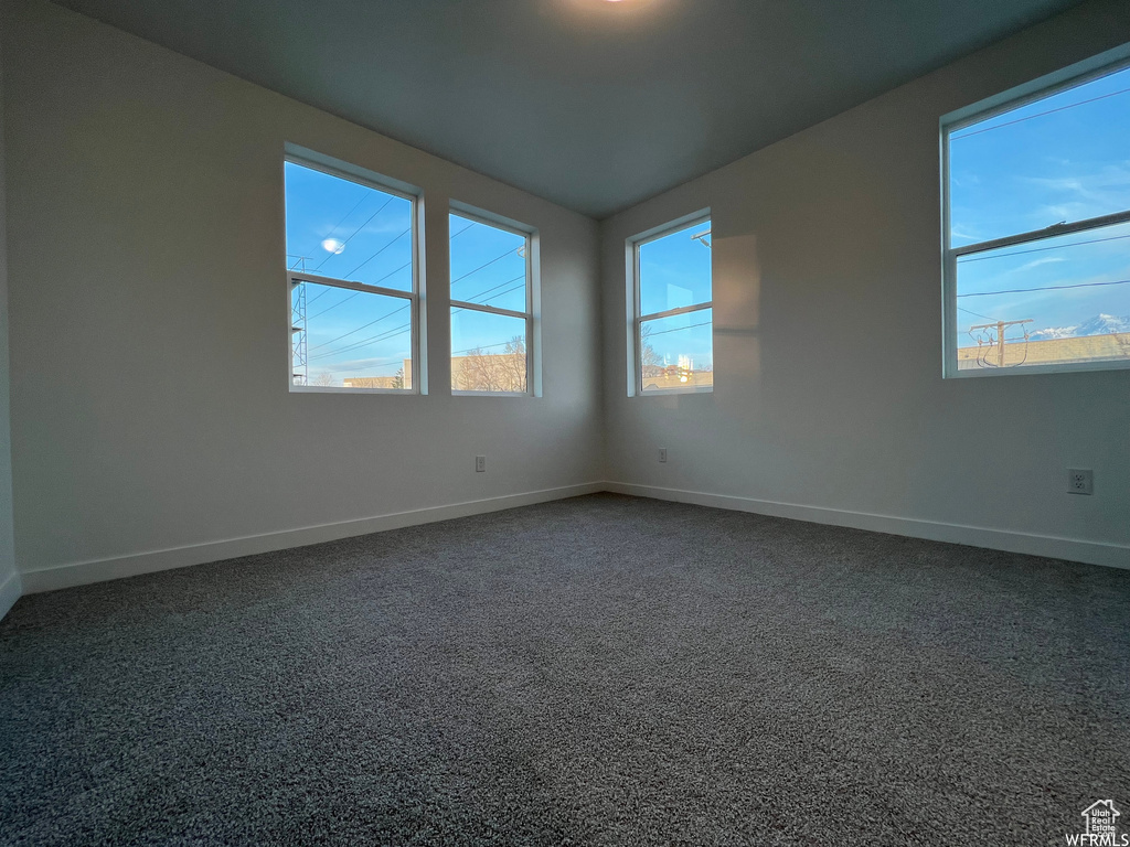 Empty room with plenty of natural light and dark carpet