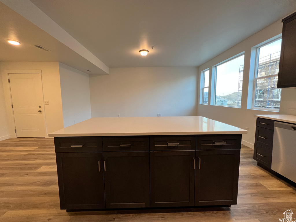 Kitchen with dishwasher, a kitchen island, dark brown cabinets, and light wood-type flooring