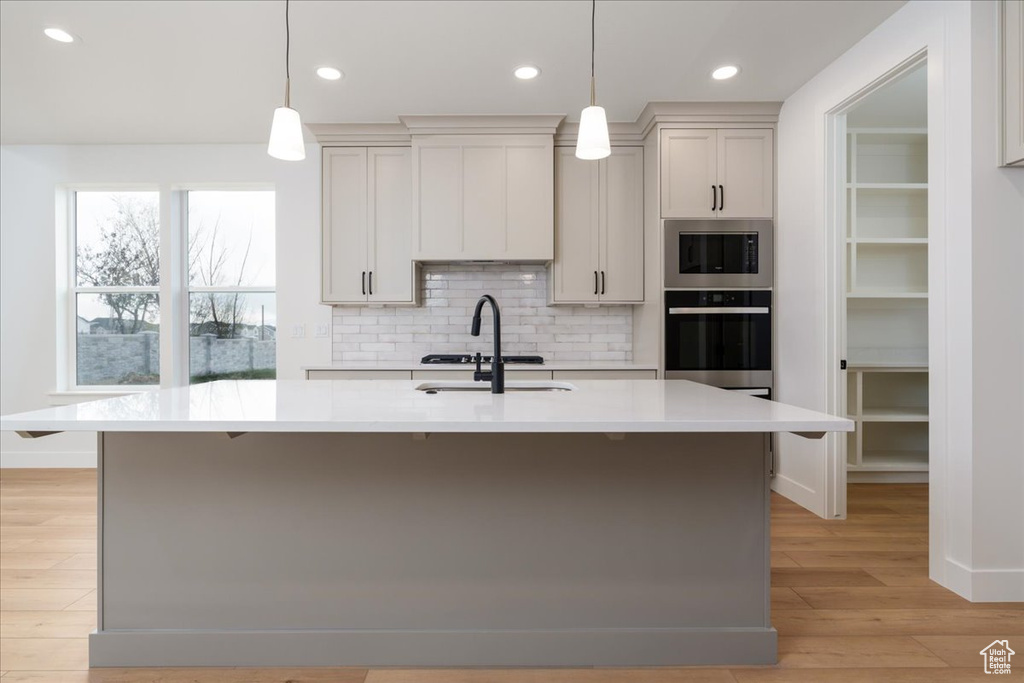 Kitchen featuring pendant lighting, an island with sink, and stainless steel appliances