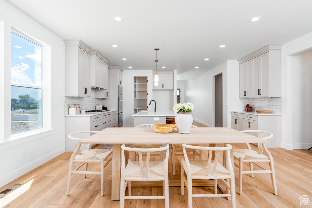 Kitchen with a center island with sink, white cabinetry, tasteful backsplash, and light hardwood / wood-style flooring