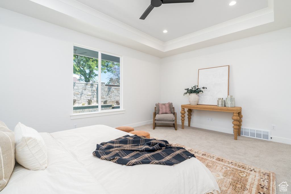 Bedroom with a raised ceiling, ceiling fan, and carpet floors