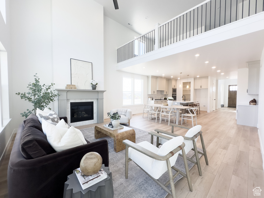 Living room featuring a towering ceiling, sink, and light wood-type flooring