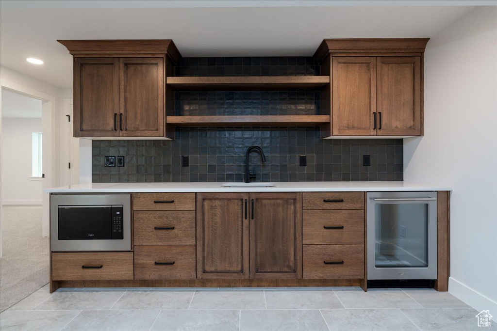 Bar featuring sink, tasteful backsplash, built in microwave, and beverage cooler