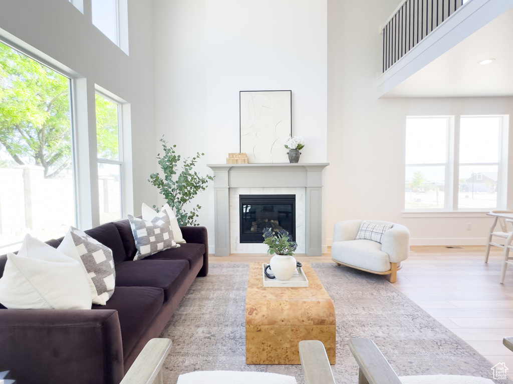 Living room with a high ceiling, a tiled fireplace, and wood-type flooring