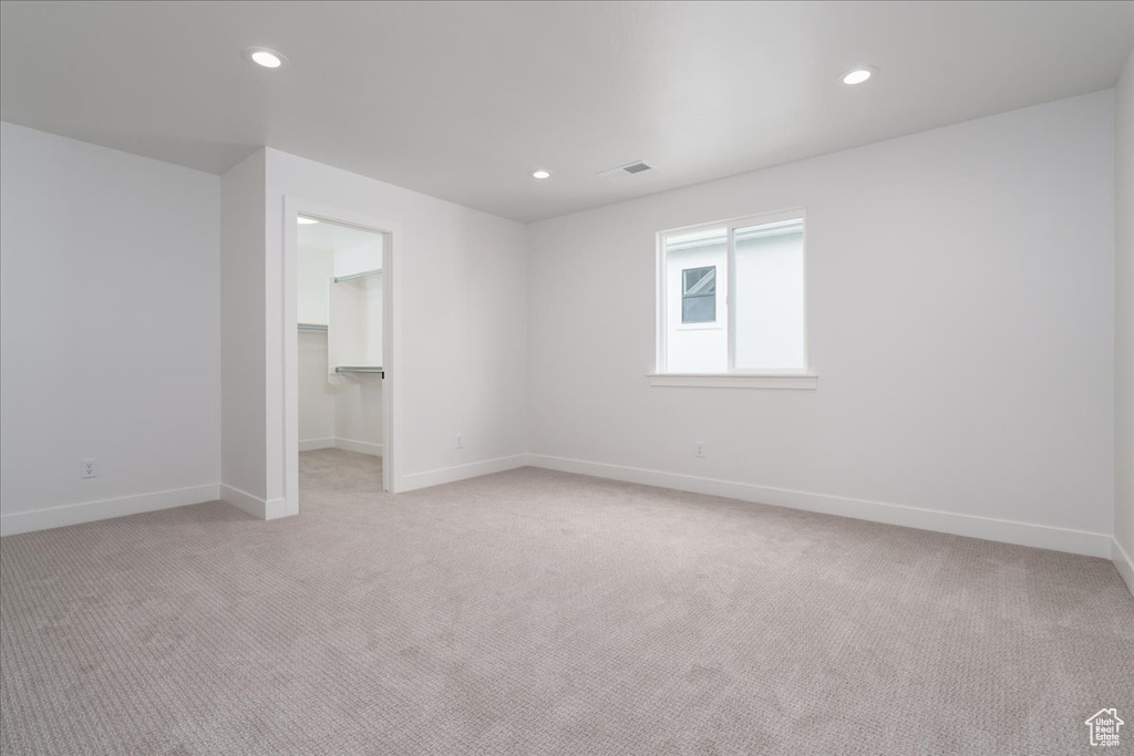 Unfurnished bedroom with a closet, a walk in closet, and light carpet