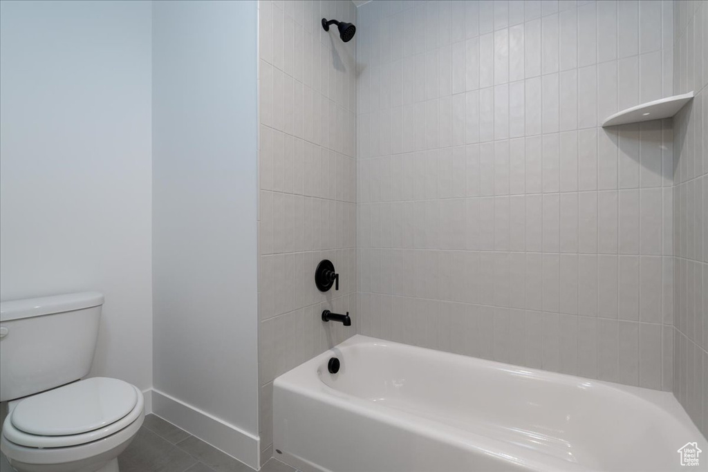 Bathroom with tile floors, tiled shower / bath combo, and toilet