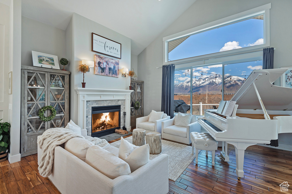 Living room with a stone fireplace, high vaulted ceiling, dark hardwood / wood-style floors, and a mountain view