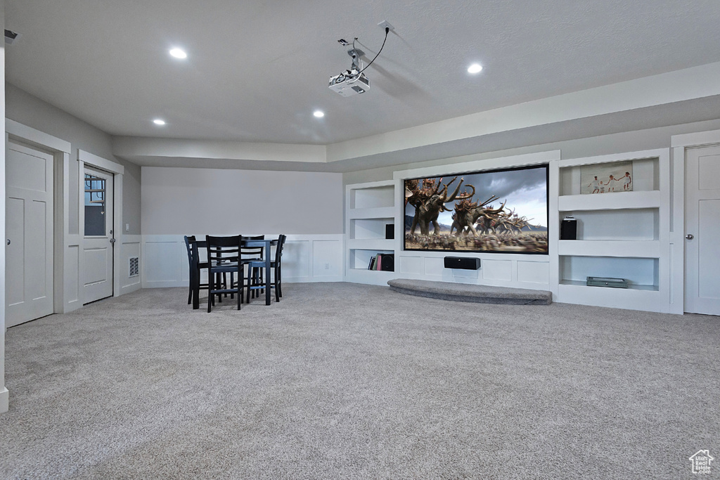 Carpeted home theater with built in shelves and a textured ceiling
