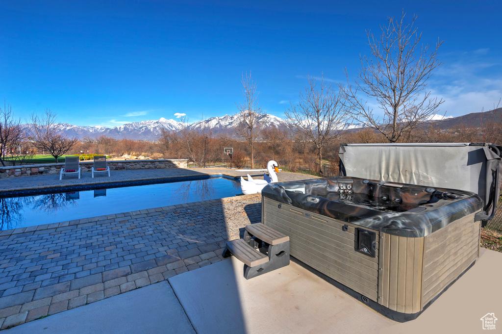 View of pool with a mountain view, a hot tub, and a patio