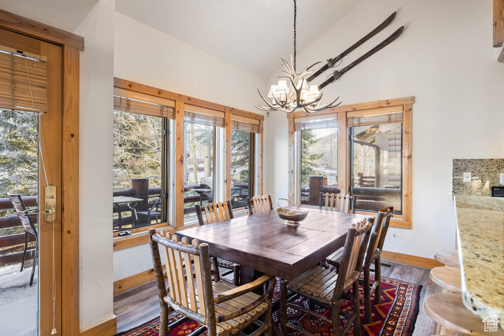 Dining area with plenty of natural light, an inviting chandelier, and hardwood / wood-style flooring