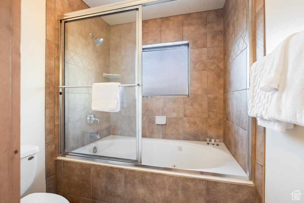 Bathroom featuring toilet and combined bath / shower with glass door