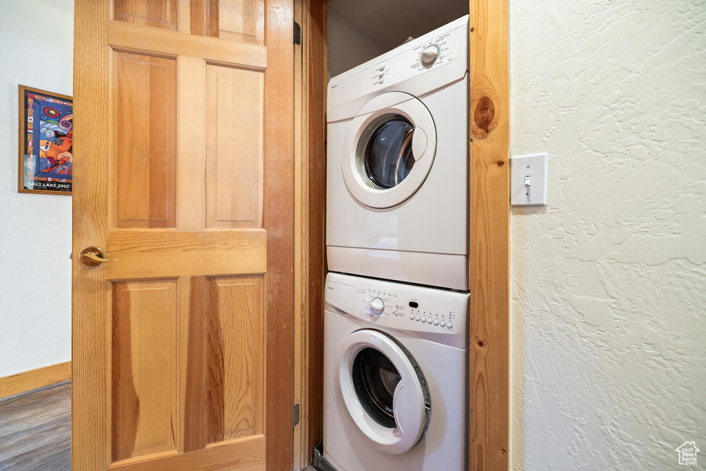 Laundry area featuring stacked washer and clothes dryer and wood-type flooring