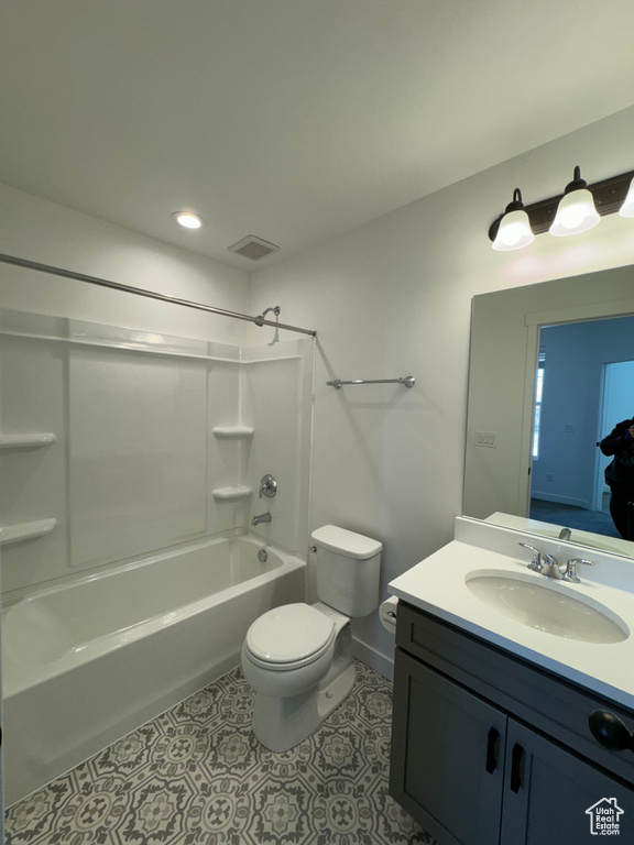 Full bathroom with tile floors, toilet, vanity with extensive cabinet space, and shower / washtub combination