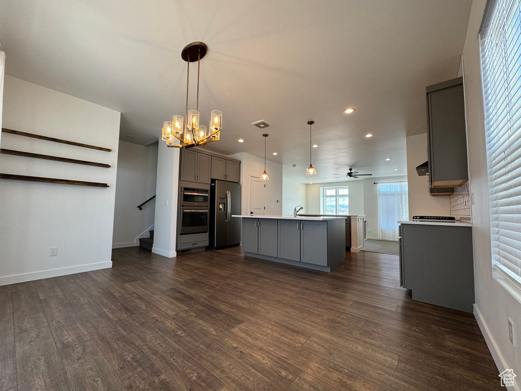 Kitchen featuring appliances with stainless steel finishes, pendant lighting, gray cabinetry, and dark hardwood / wood-style flooring