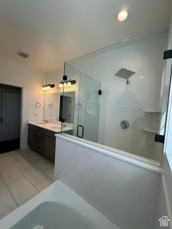 Bathroom featuring a shower with shower door, double sink vanity, and tile floors