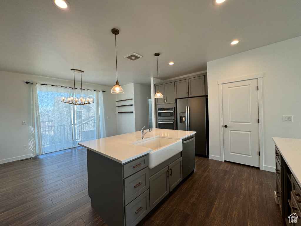 Kitchen with an inviting chandelier, decorative light fixtures, stainless steel appliances, and dark wood-type flooring