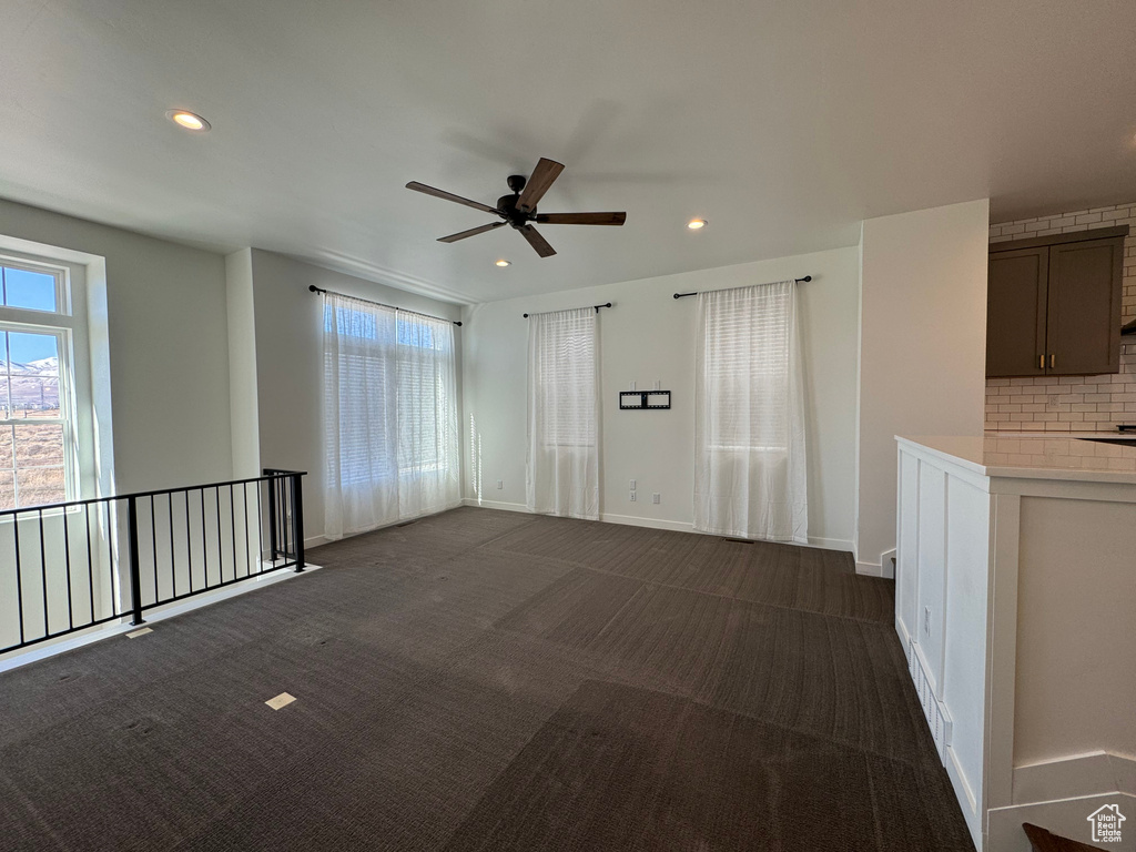 Unfurnished room featuring dark colored carpet and ceiling fan